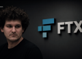 Man with curly hair in a black shirt, looking away, against a dark wall with the blue-and-white FTX logo.