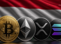 Gold Bitcoin coin beside Ethereum, XRP, and Solana coins with a red‑white‑black flag backdrop.