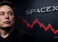 Elon Musk gazes to the left with a blurred SpaceX sign and a red stock chart in the background behind him.