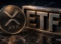 Close-up of a Ripple XRP coin beside a metallic ETF sign on a dark marble surface.