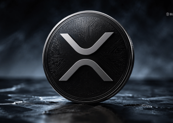 Close-up of a glossy XRP cryptocurrency coin with a silver logo against a dark smoky background.