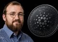 Man with glasses and a beard smiles beside a large metallic cryptocurrency coin against a black background.