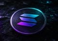 Close-up of a Solana cryptocurrency coin with a blue–purple gradient on a dark textured surface.