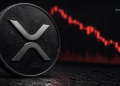 Close-up of a Ripple (XRP) coin with circuitry design, set against a red downward-trending price chart backdrop.