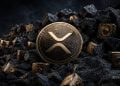A large gold XRP coin sits among dark jagged rocks with small gold lockboxes, evoking crypto mining. (No logo text shown)