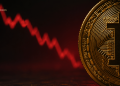 Close-up of a gold Bitcoin coin on the right with a red fluctuating chart in a dark background, BLOCKNEWS logo visible on the left.